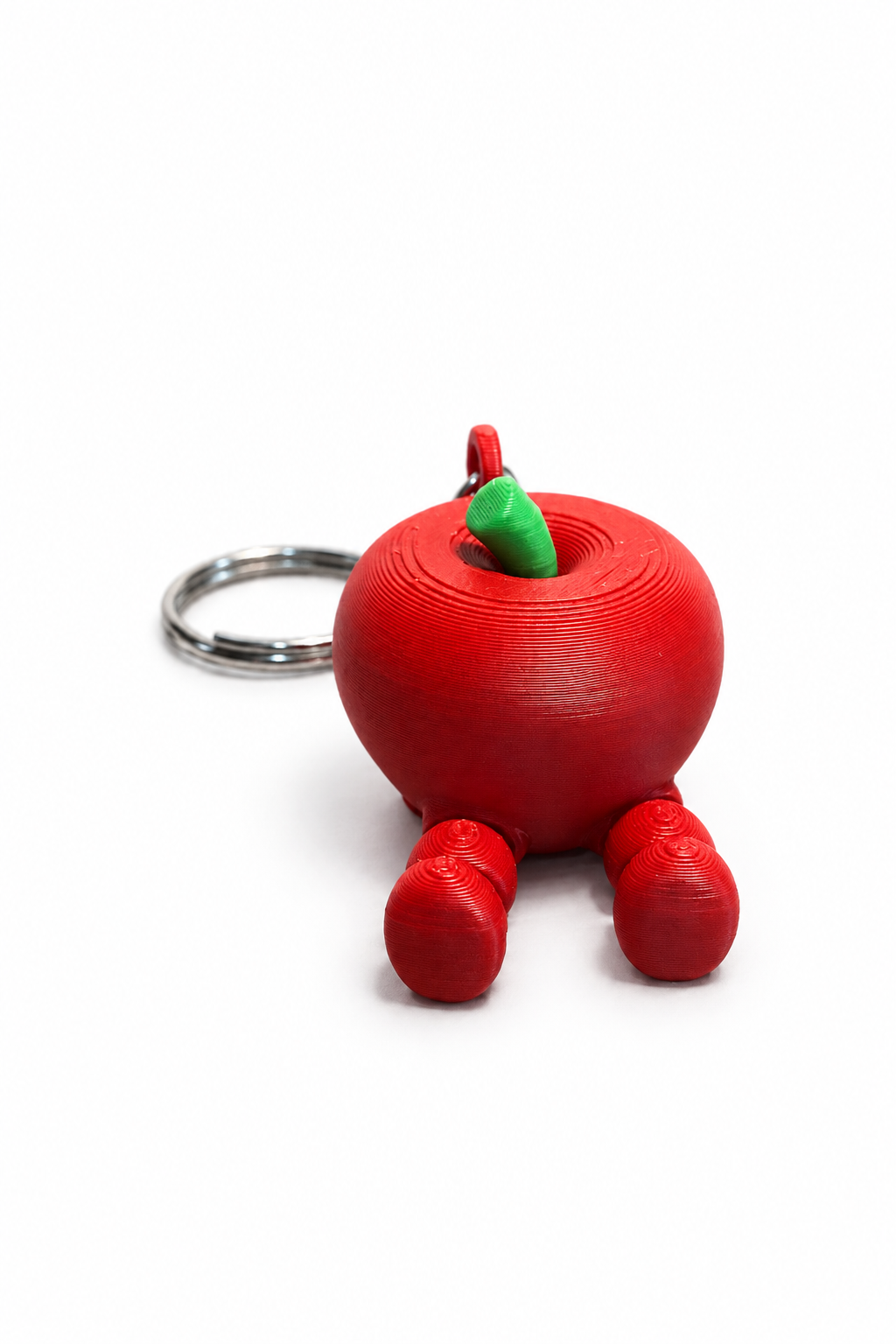 Red 3D printed apple keychain with green leaf and articulated legs on a white background