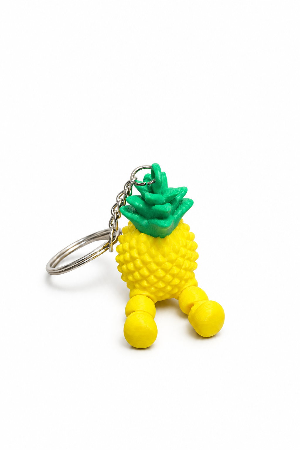 Yellow and green articulated pineapple keychain with metal ring on a white background