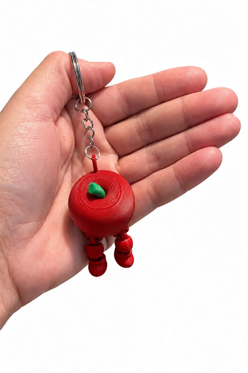 Red apple keychain held in a hand against a white background